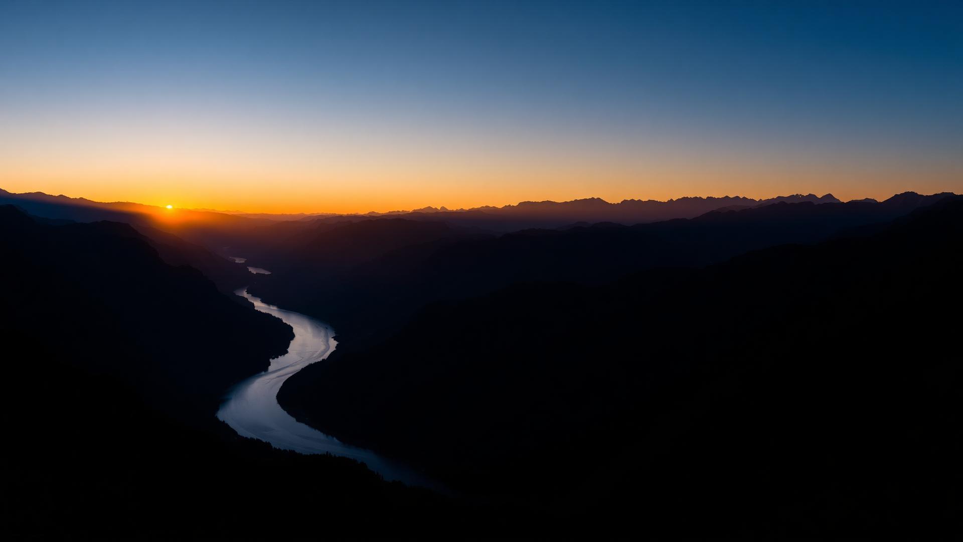 A river winding through mountain ridges at sunrise